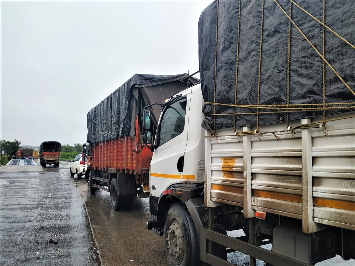 A line of trucks, each loaded with rescued horses, drives up the road.