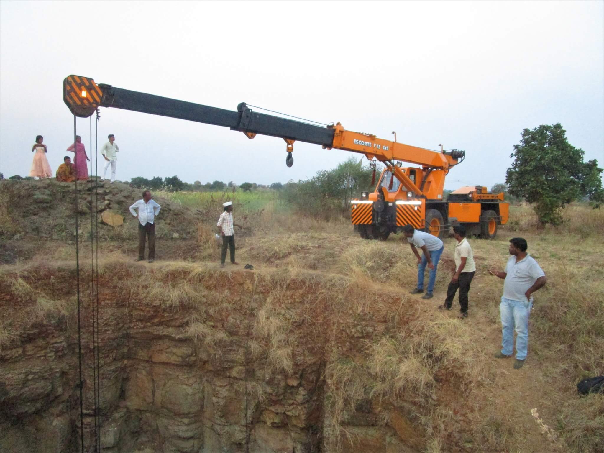 A crane and the rescue team gather at the edge of the well.