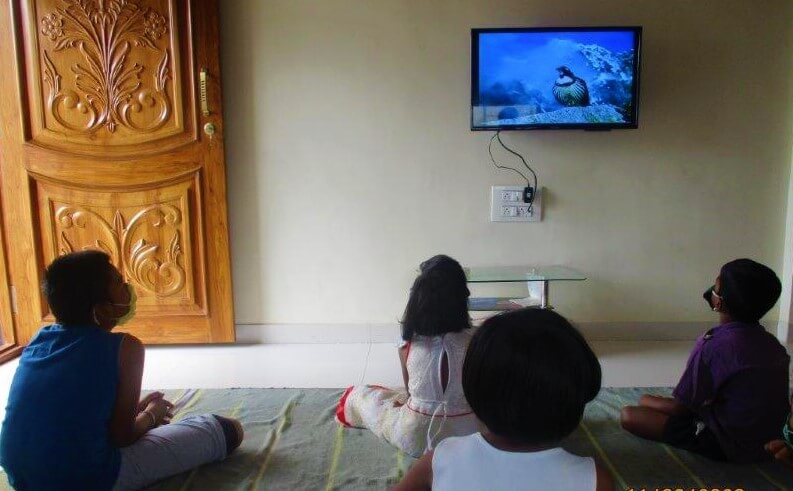 Students watch a video of an Animal Rahat rescue during a Compassionate Citizen lesson at their teacher's home.