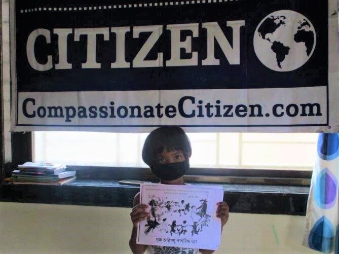 A student stands below a Compassionate Citizen banner and holds a copy of the program's "Share the World" poster.